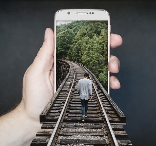 Uomo che cammina sui binari del cambiamento entrando in un telefono che rappresenta l'innovazione